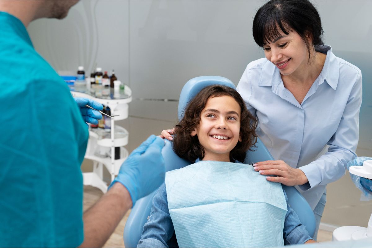 A smiling child sitting on a dentist's chair with pediatric dentist