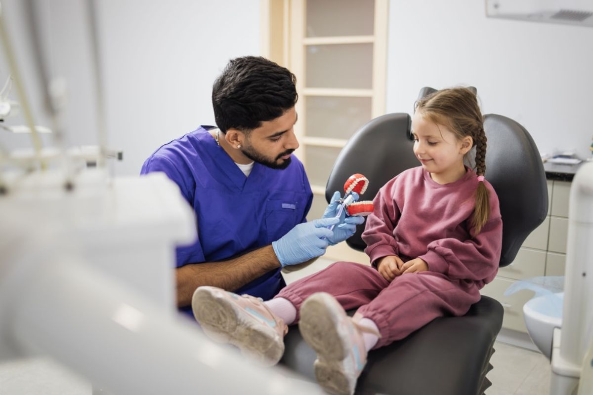 Pediatric dentist helping a child feel comfortable during a dental check-up with friendly care.