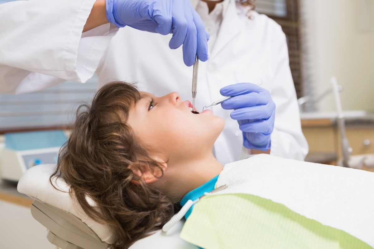 Pediatric dentist treating a child with a dental injury in a calm and friendly environment.