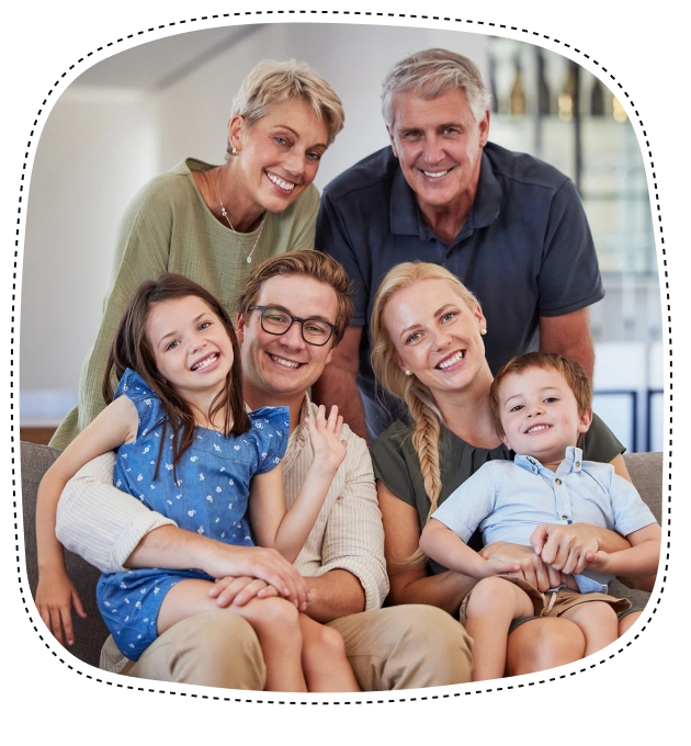 Multi-generational family smiling together indoors in casual clothing.