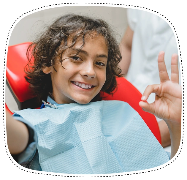 Young boy smiling in dental chair wearing bib during pediatric dental examination