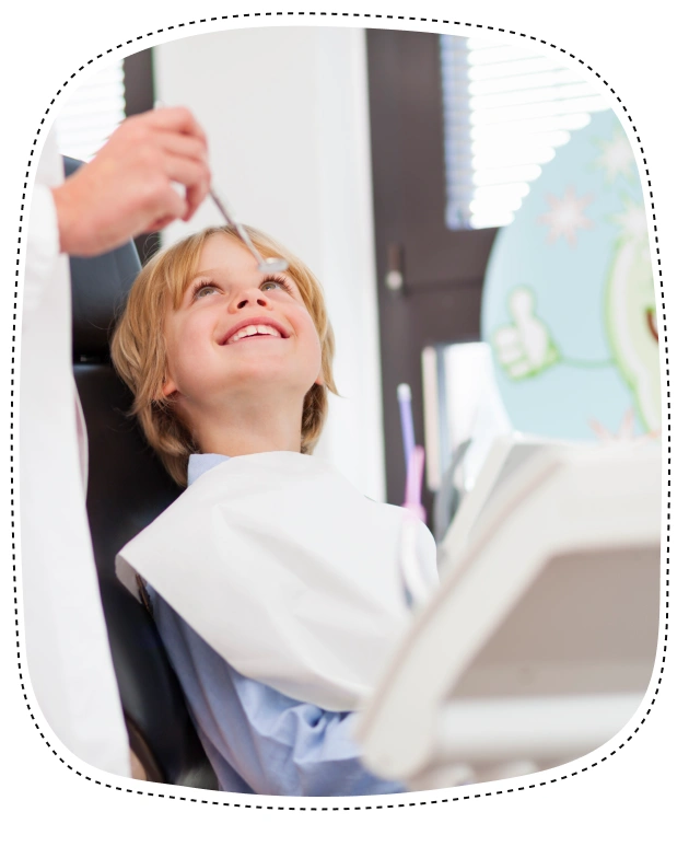 Young child in dental chair looking up during examination with dentist above.