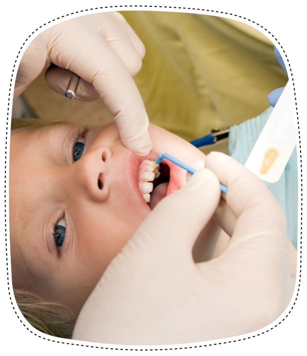 Pediatric dentist examining young child's teeth during dental checkup.