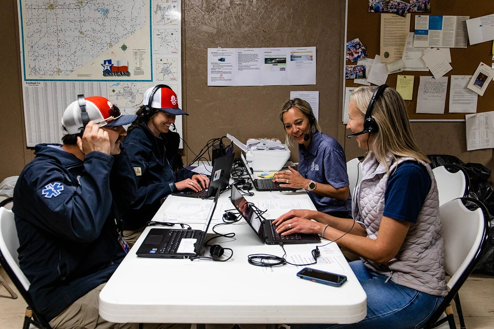 Four women in dental uniforms sit at table during staff meeting or training session in office.