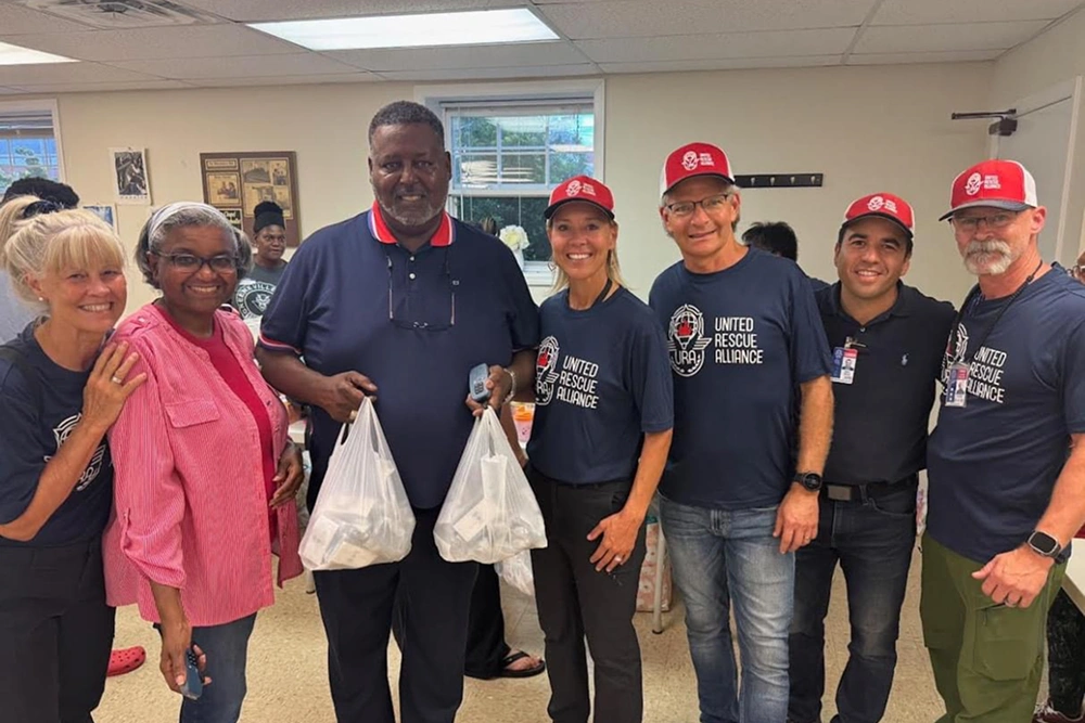 Group of dental staff and volunteers holding donation bags in indoor clinic setting.