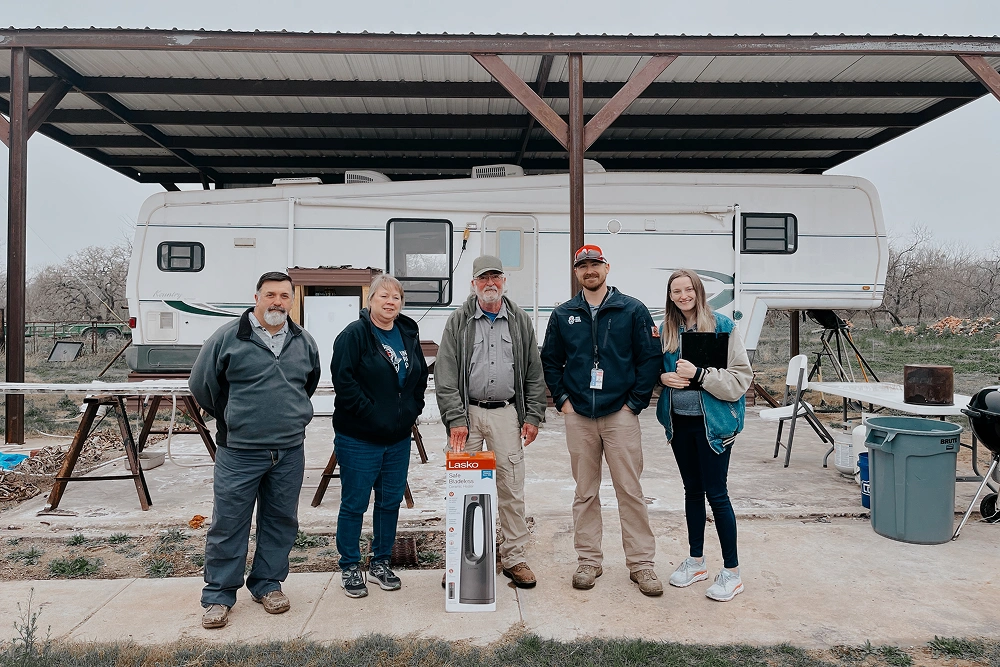 Team members standing in front of mobile dental clinic trailer at outdoor location.