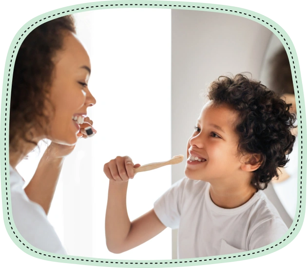Adult and child brushing teeth together in a bright, clean indoor setting.