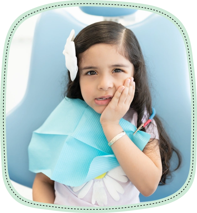 Young girl with hand to cheek against blue background, suggesting dental discomfort or tooth pain.
