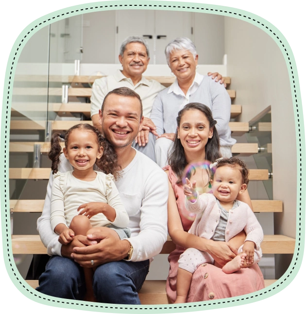 Happy multi-generational family smiling together on wooden stairs in home setting.