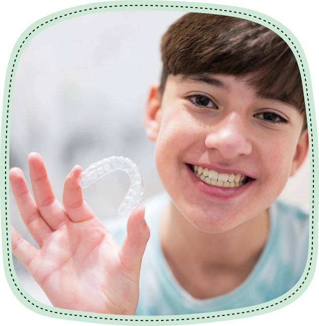 Smiling child holding a tooth model against white background for dental education.