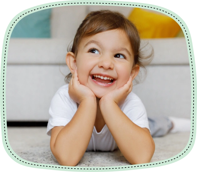 Happy toddler smiling brightly while lying on floor in playful pose.