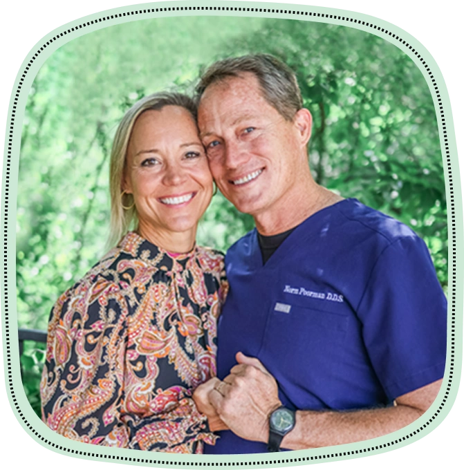 Two smiling adults posing together outdoors with green foliage background.